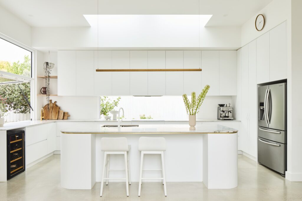 all white kitchen with curved island bench and servery window
